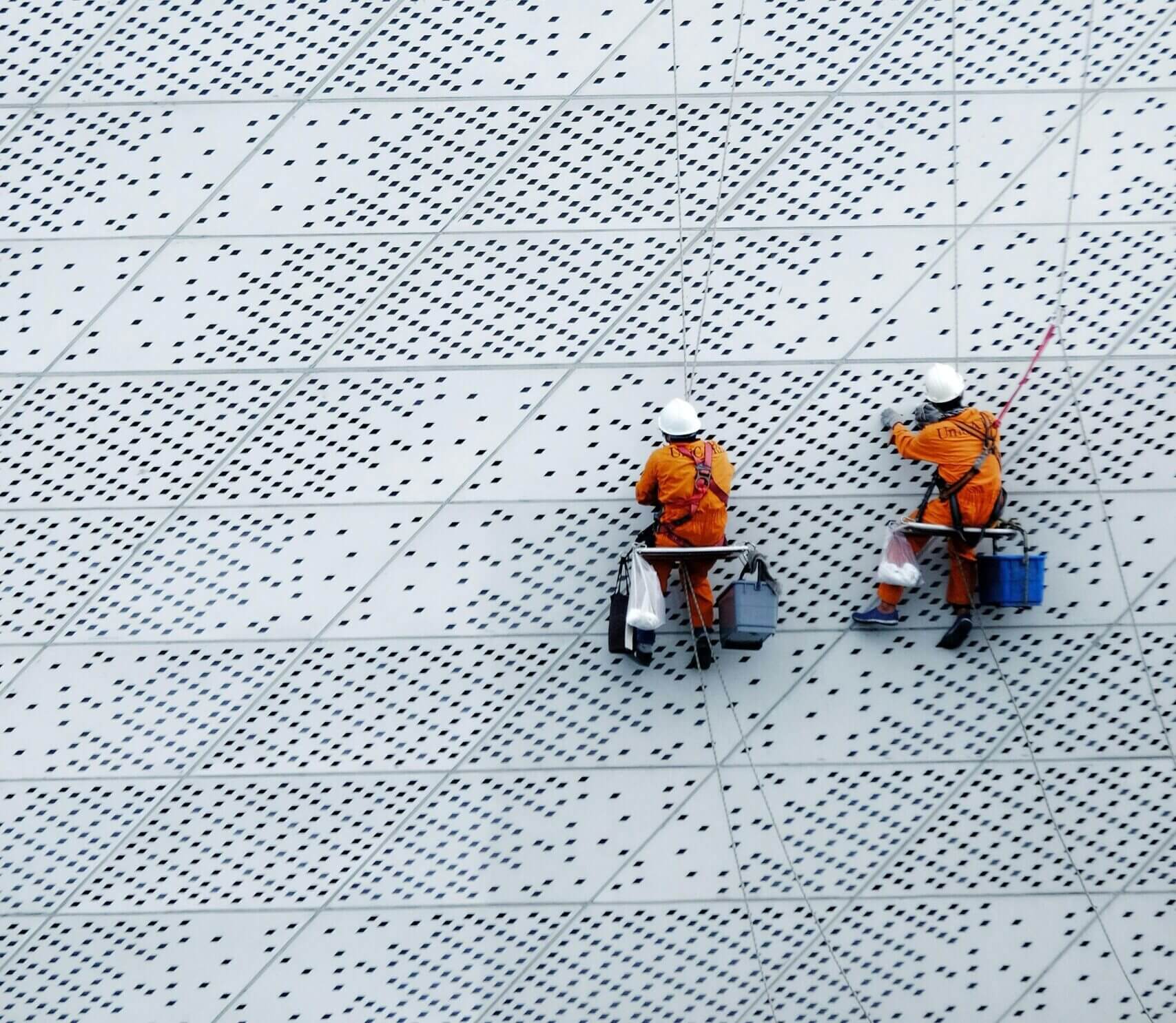Two workers clean a building exterior Two workers clean a building exterior